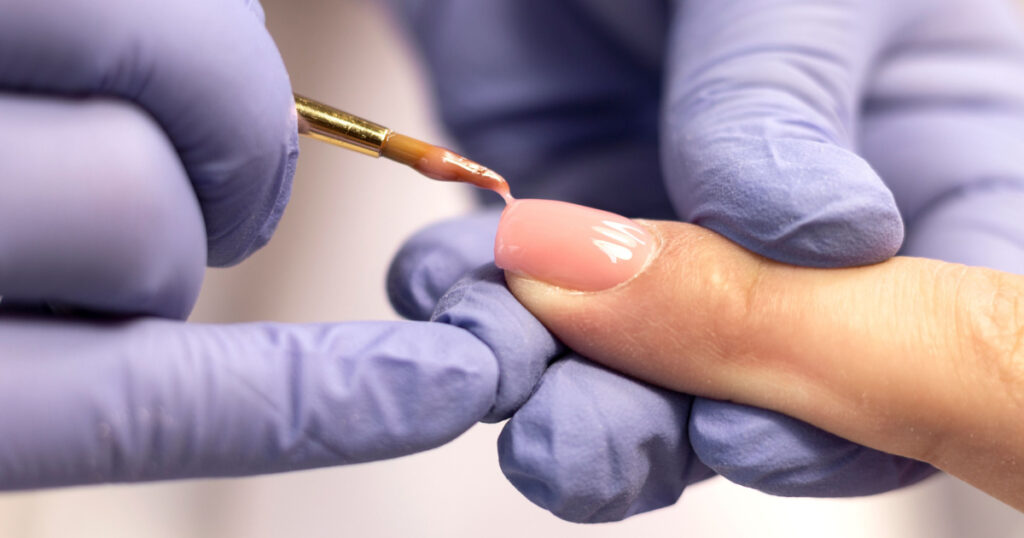 Manicure. Strengthening of natural nails with artificial material-gel. Nail care in a beauty salon. Close-up

