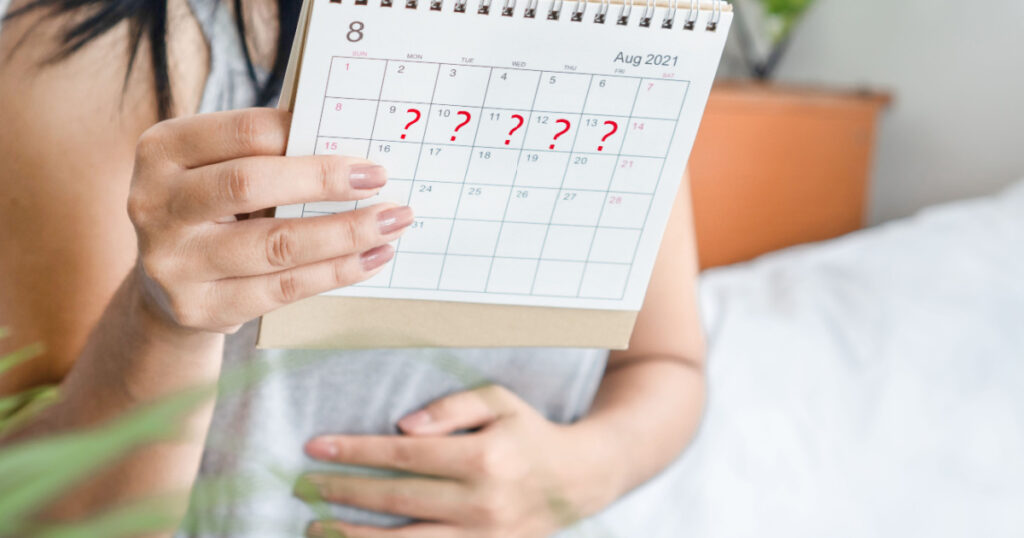 woman hand holding calendar with question mark waiting for late blood period, amenorrhea, irregular periods concept