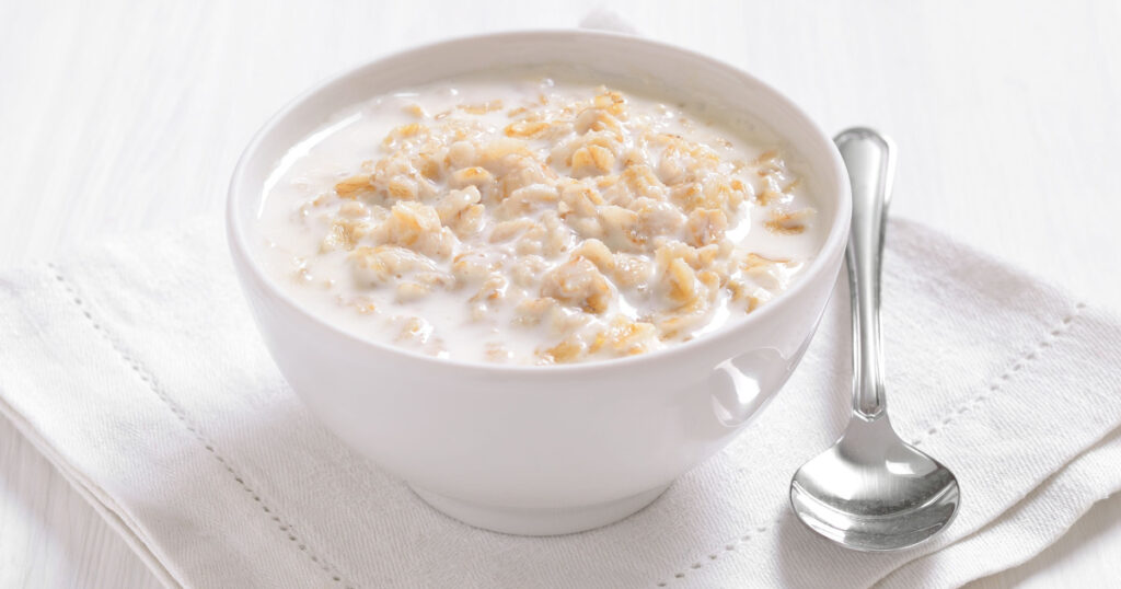 Oatmeal porridge in white bowl, close up view.