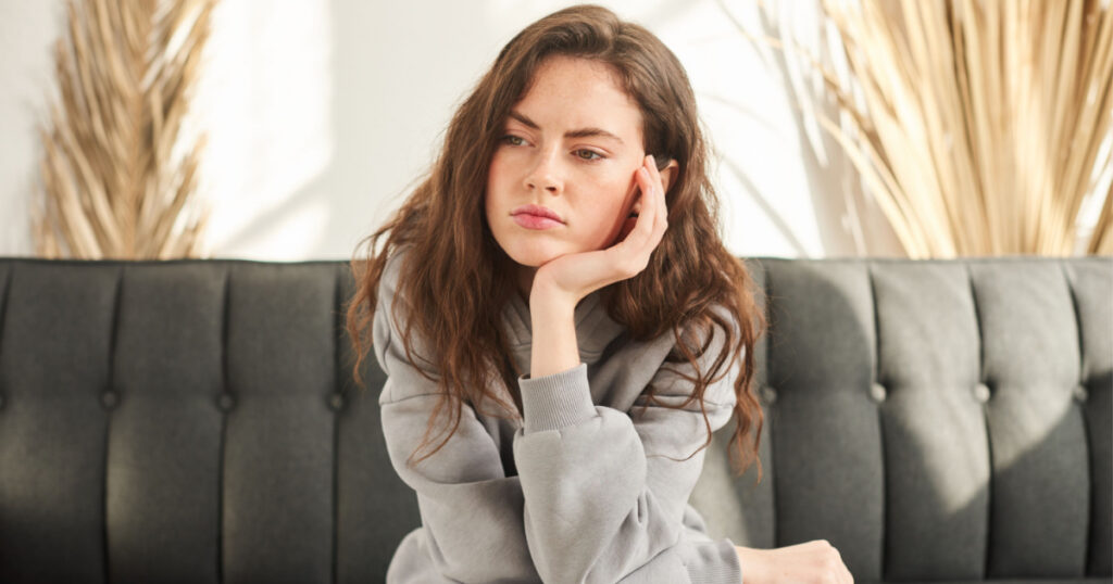 bored and sad woman sitting on couch with no mood and prop up head with hand