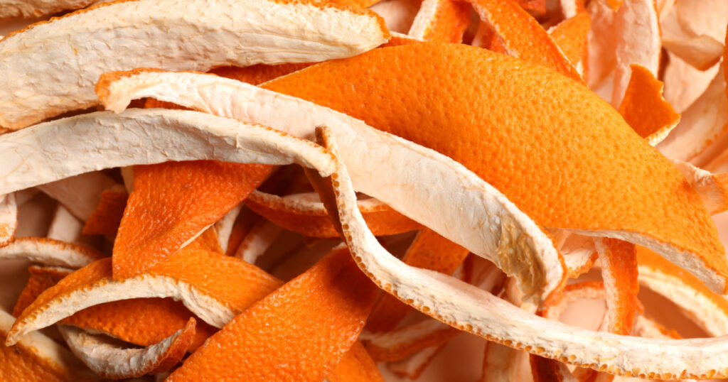 Many dry orange peels on white table, closeup