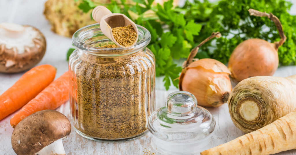 Homemade vegetable broth powder, organic vegetable stock, with raw vegetables on white wooden background