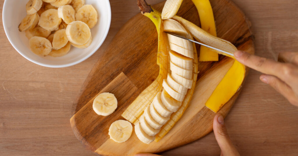 woman cutting banana slices. sliced banana. banana slices. preparing fruit salad. healthy foods.