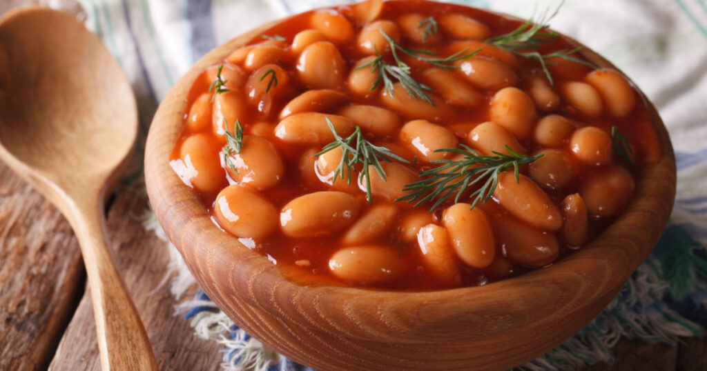 white beans in tomato sauce in a wooden bowl closeup. horizontal