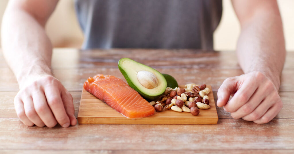 healthy lifestyle, diet and people concept - close up of male hands with food rich in protein on cutting board on table