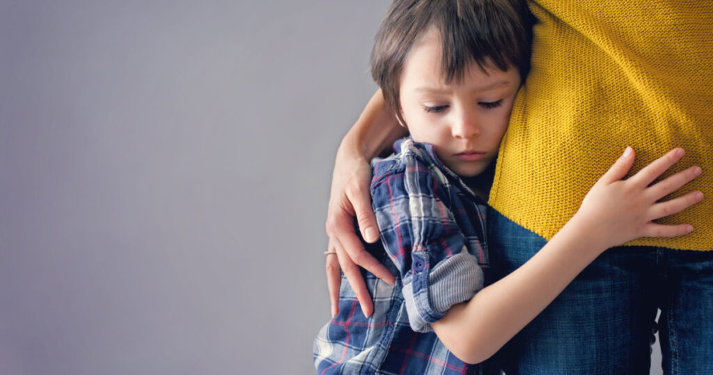 Sad little child, boy, hugging his mother at home, isolated image, copy space. Family concept