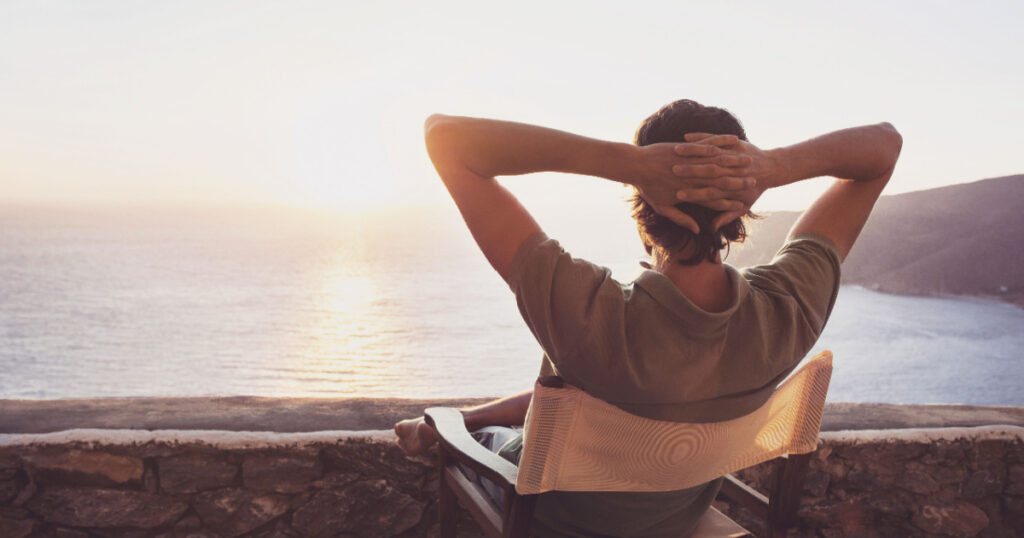 Enjoying life. Back side of young man looking at the sea, vacations lifestyle concept