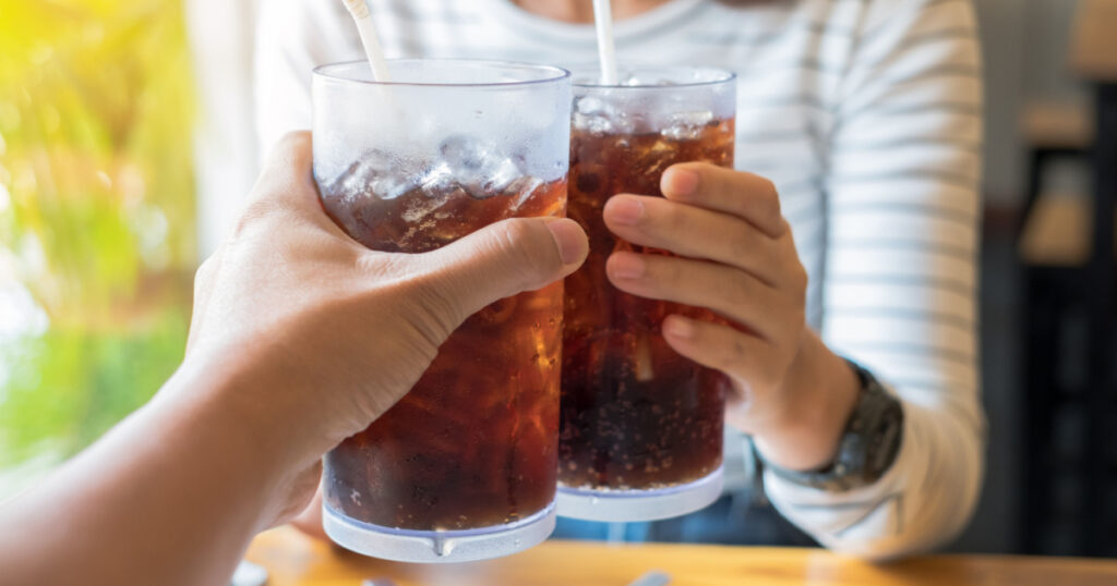 Men and Woman hand giving glass of cola.Glass of cola ,Soft drinks with ice, sweetheart or buddy
