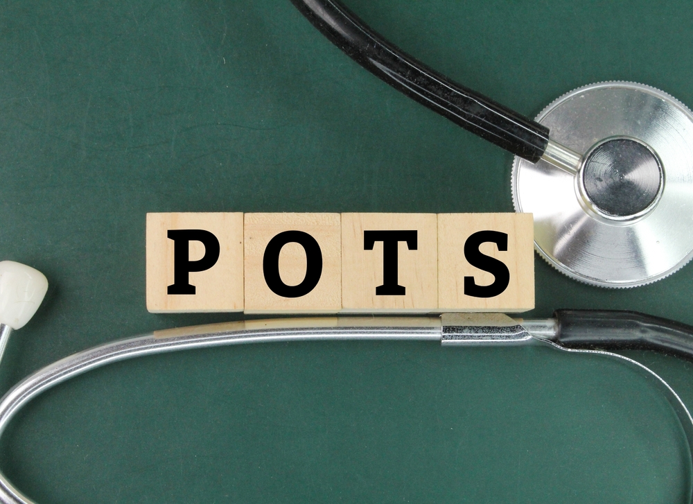stethoscope and the letters POTS or the word Postural Orthostatic Tachycardia Syndrome. symptoms when you transition from lying down to standing up
