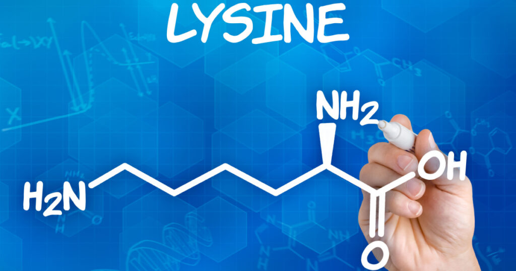 Hand with pen drawing the chemical formula of lysine