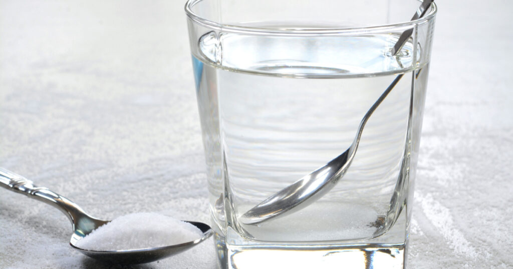 Salt water in a glass cup and salt in a teaspoon. Salt water has high level of minerals and salt water gargle helps in removing of cold and sore throat