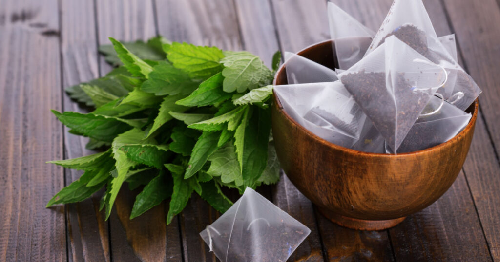 Tea bags on wooden background. Fresh melissa, mint. Selective focus.