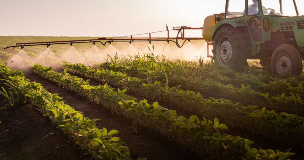 Tractor spraying pesticides on soy field with sprayer at spring
