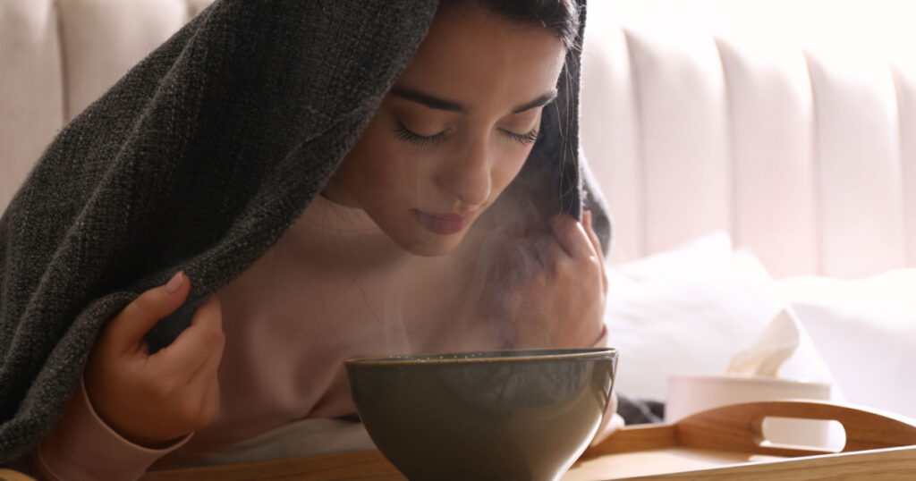 Woman with plaid doing inhalation above bowl indoors