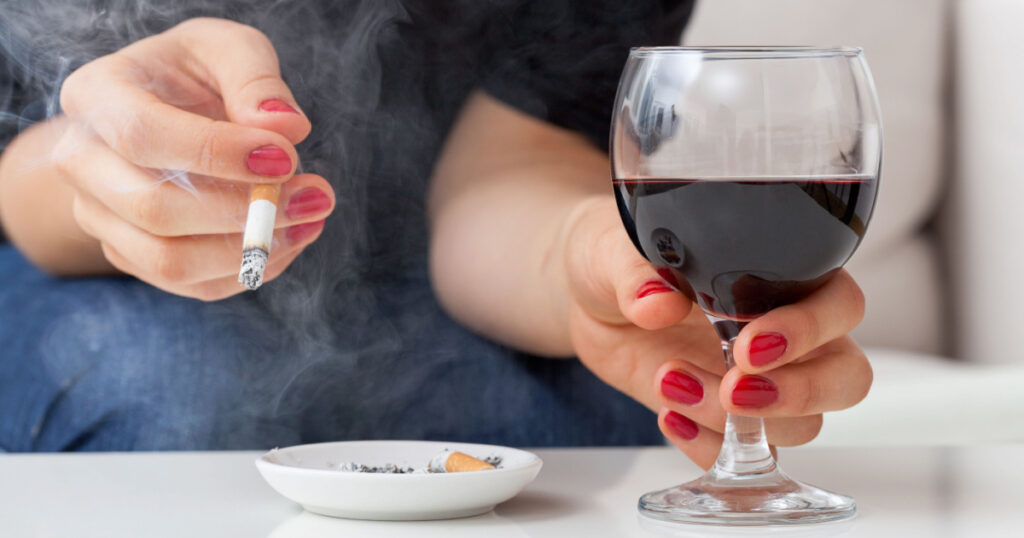 Woman is smoking cigarette and drinking alcohol
