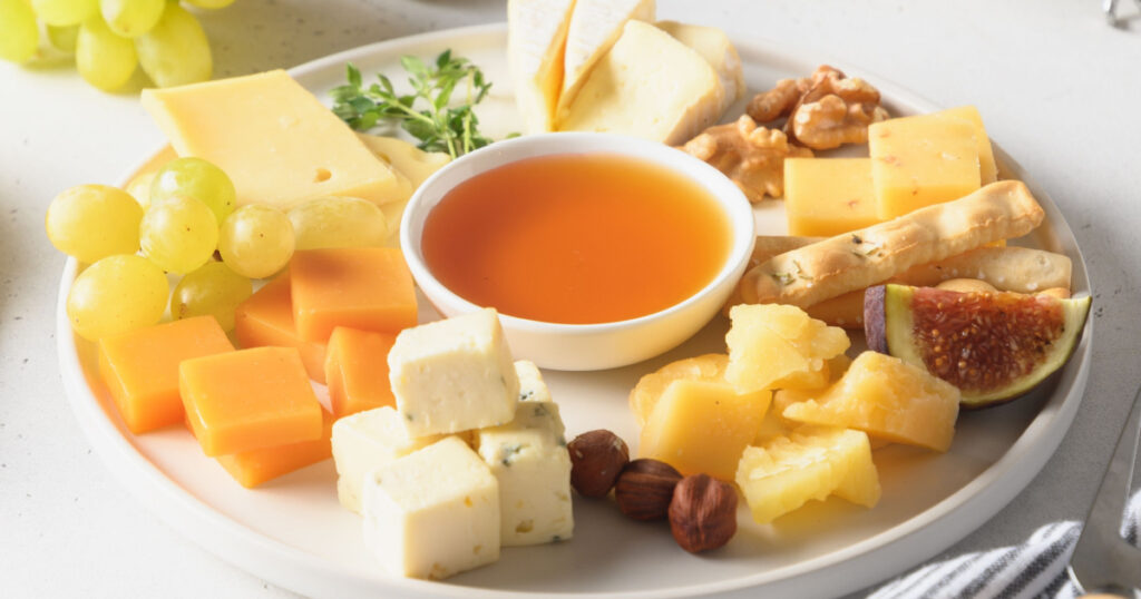 Cheese platter with fruits on a white background. Close up. Festive gourmet snack.
