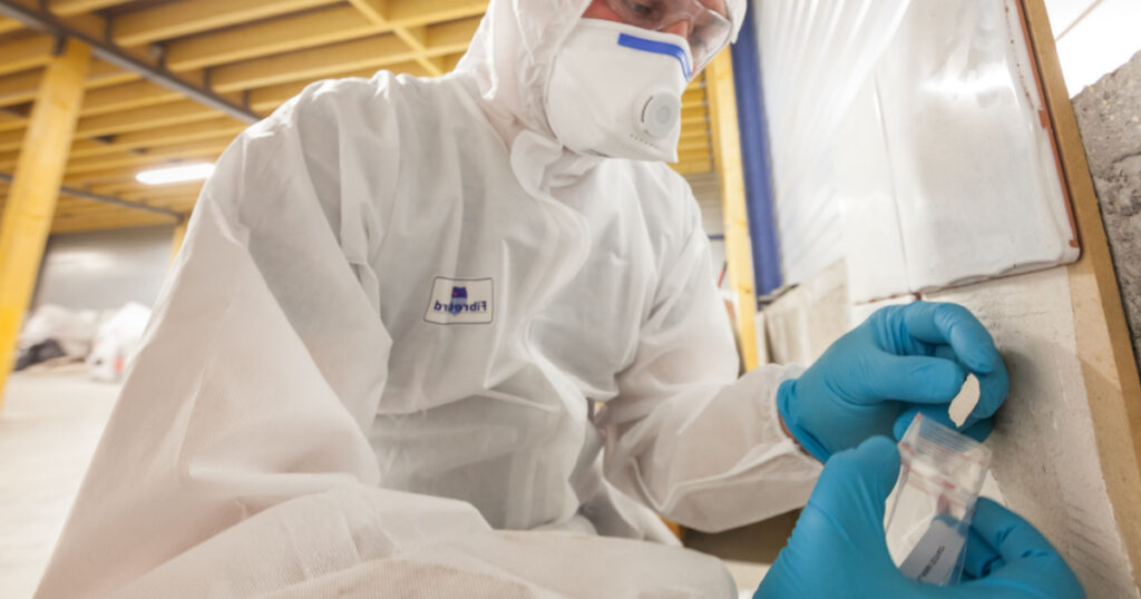 Asbestos surveyor taking a sample of building material, detection of asbestos, in accordance with the recommendations of standard NF X 46-020
