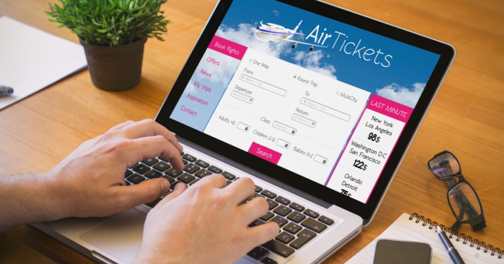 Close-up top view of man working on laptop with tickets flights web. all screen graphics are made up.
