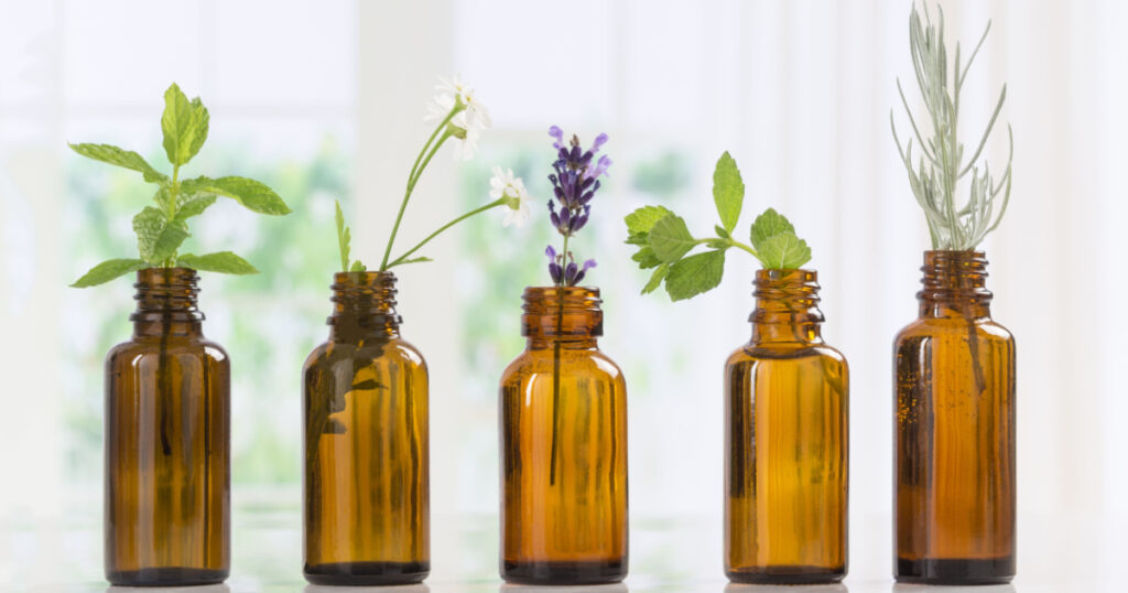 Brown Bottles of essential oil with fresh herbs