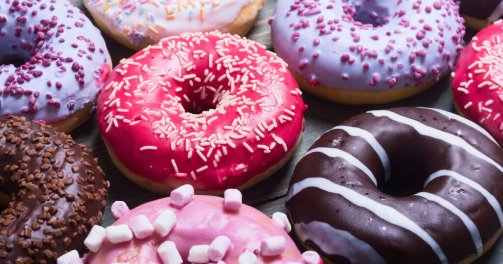 assorted donuts with chocolate frosted, pink glazed and sprinkles donuts.