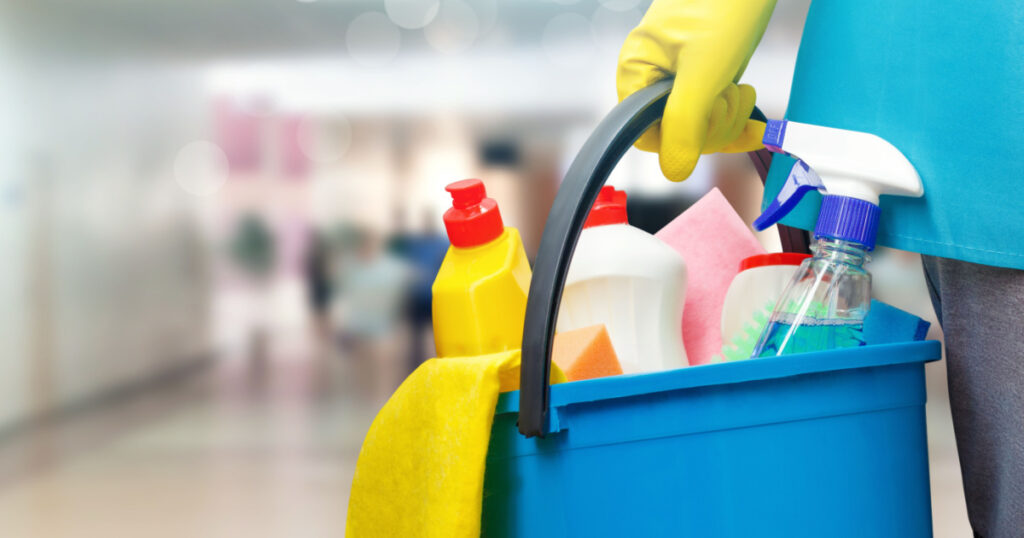 Cleaning lady with a bucket and cleaning products on blurred background.

