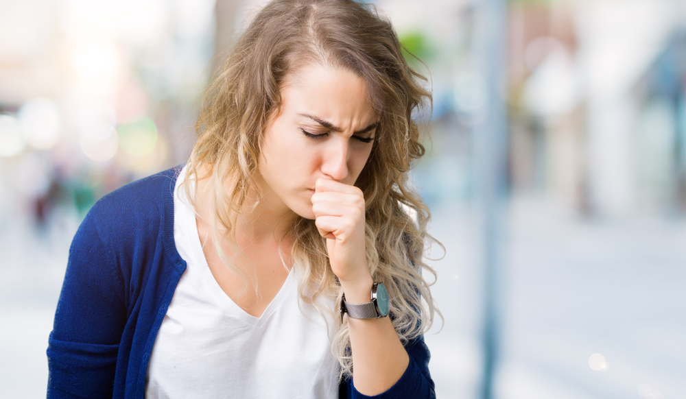 Beautiful young blonde woman over isolated background feeling unwell and coughing as symptom for cold or bronchitis. Healthcare concept.