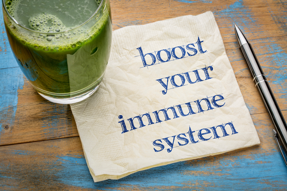 boost your immune system - inspirational handwriting on a napkin with a glass of fresh, green, vegetable juice, healthy lifestyle and wellbeing concept
