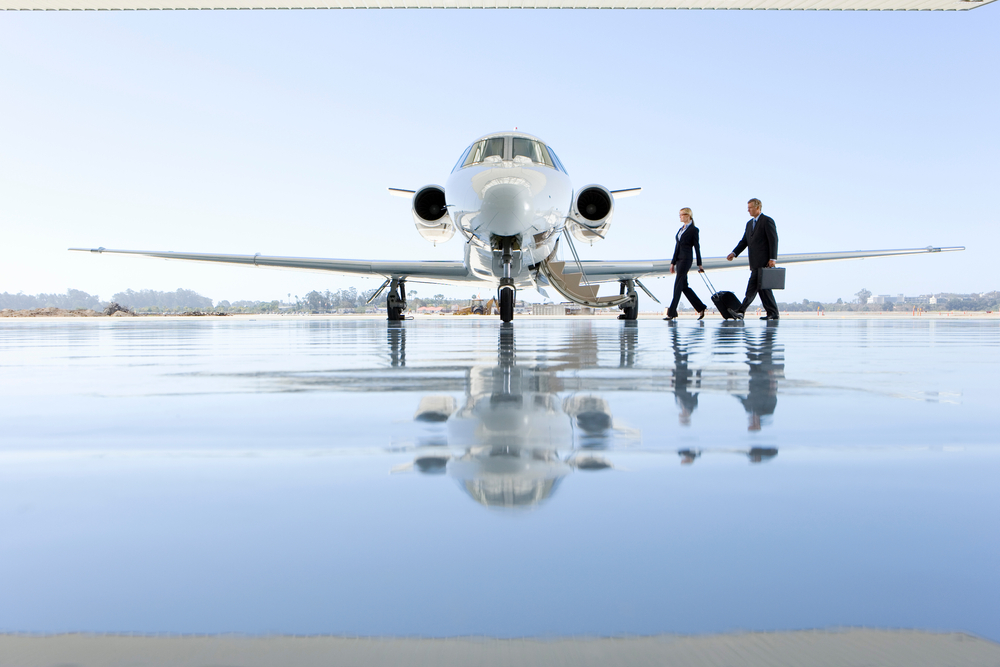 Wide shot of a pilot and flight attendant walking towards the private jet on the runway.