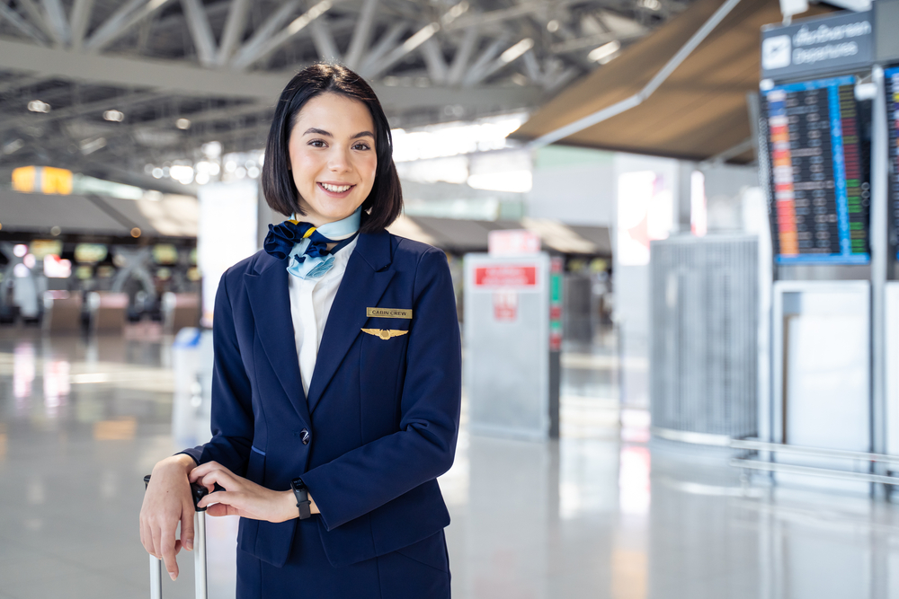Portrait of beautiful Caucasian flight attendant staff smiling and looking at camera with confidence face and happiness in airport terminal. Feeling welcome all customer or passenger to the airplane.