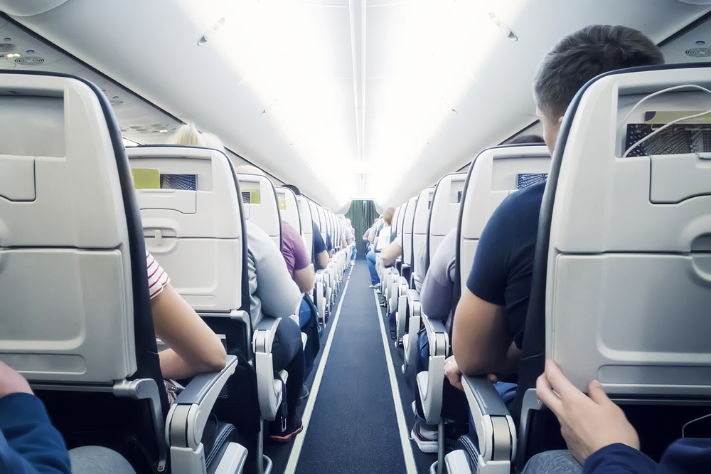 Interior of airplane with passengers on seats. Flying in economy class aircraft low-cost airline. Inside the flight
