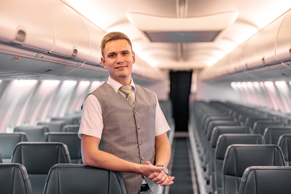 Male flight attendant standing in aircraft passenger salon