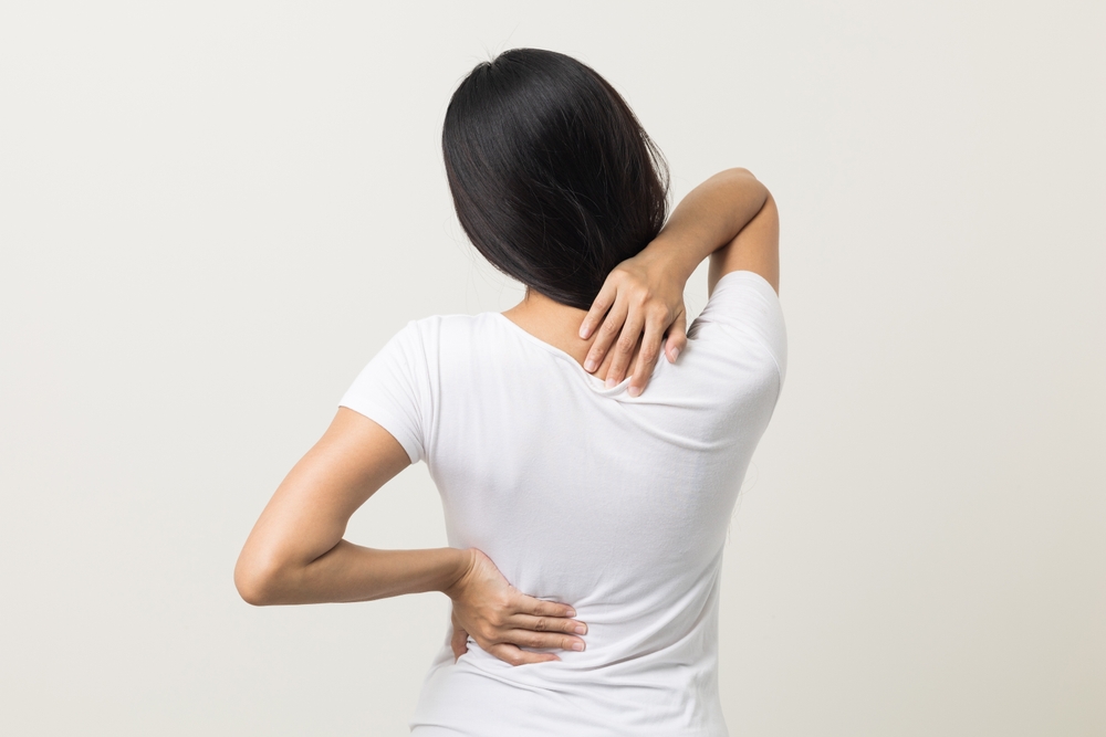 Asian woman has problem with structural posture She had neck and back pain. She massaged her neck and shoulders for relief. reduce muscle tension. Standing on isolated white background