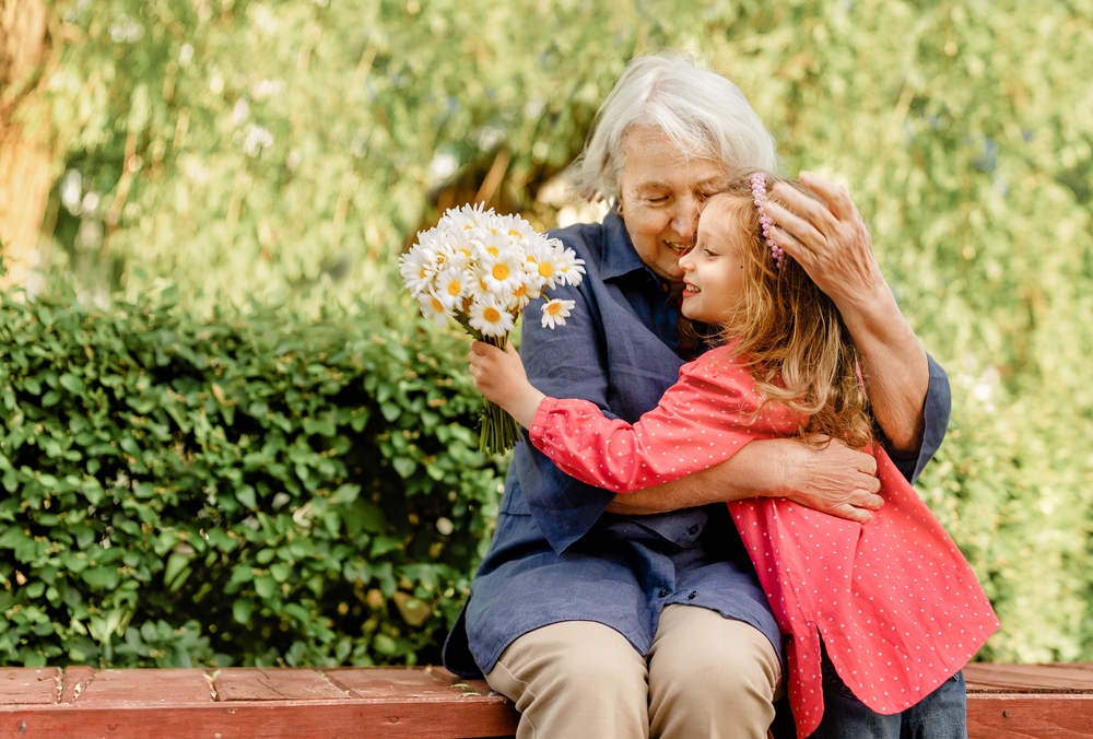 happy and laughing grandmother and her granddaughter in the park on a bench. Joyful meetings of family members
