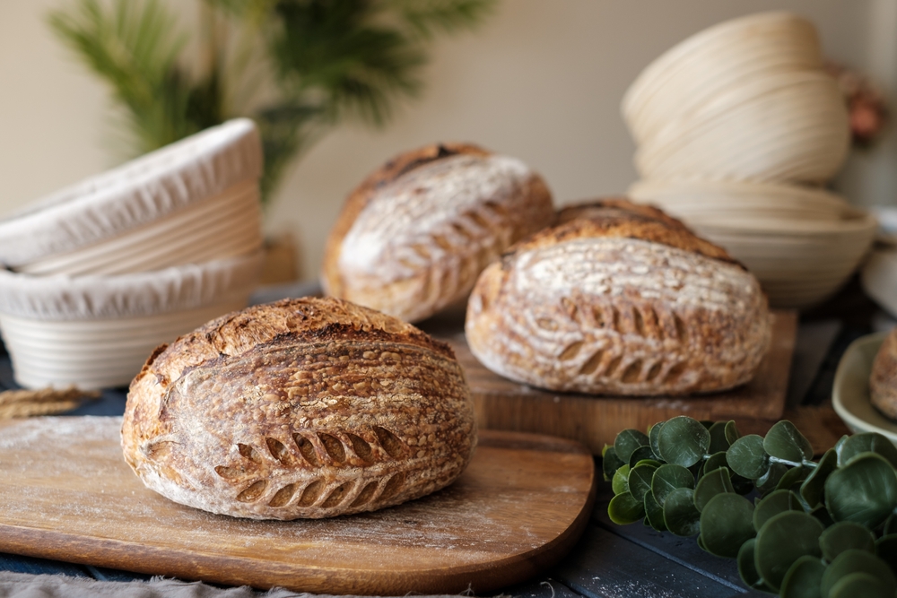 Artisan Batard Sourdough healthy Bread with leaf scoring. Open crumb high hydration Sourdough bread set on white table.