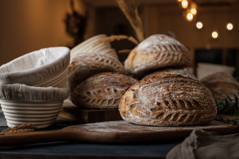 Artisan Batard Sourdough healthy Bread with leaf scoring. Open crumb high hydration Sourdough bread set on white table.