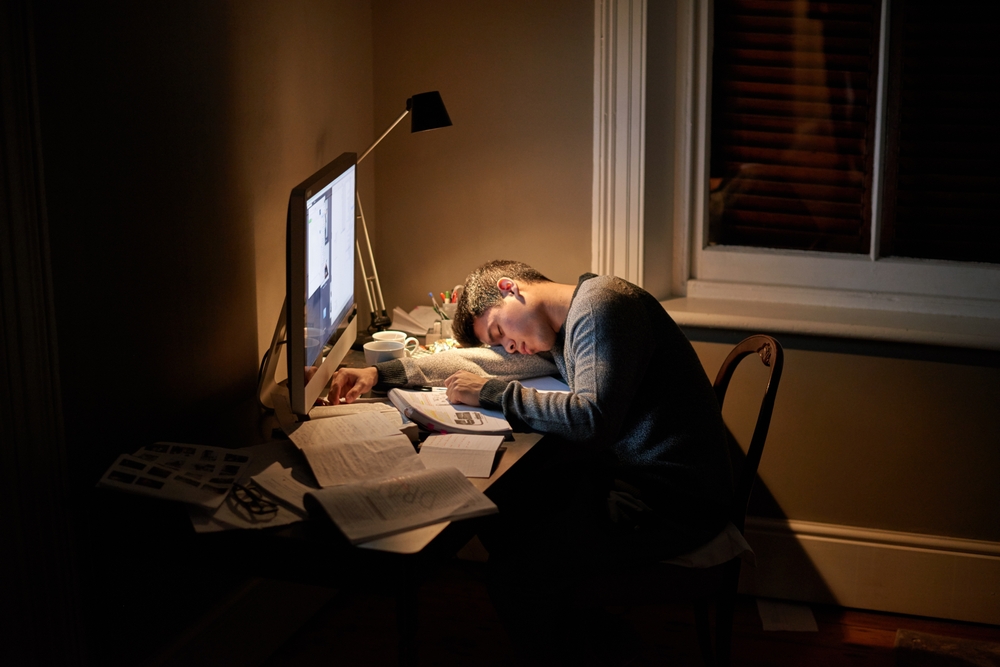 Student, university and sleeping or studying late into the night on screen or fatigue on table and reading for examination. Tired, research and hard work for test paper or computer at college
