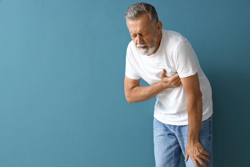 Mature man having heart attack on blue background
