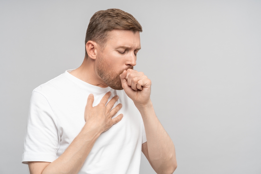 Sick man suffers bad cough, sore throat, chest pain isolated on studio grey background. Health problem bronchitis cough seasonal cold, tracheitis, illness. Banner poster for medical advertisement.