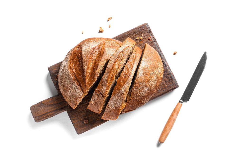 Fresh sliced Sourdough Bread on wooden cutting board isolated on white background. Yeast rye or wheat artisan bread, design element.