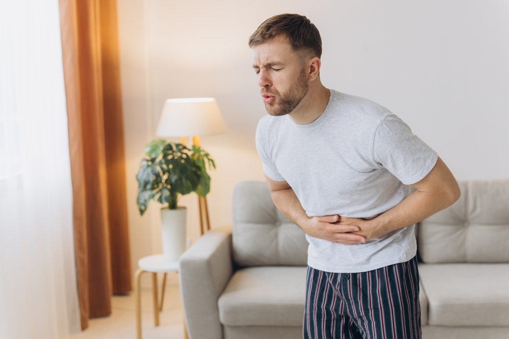 Stomach ache, man with abdominal pain suffering at home, health problems concept
