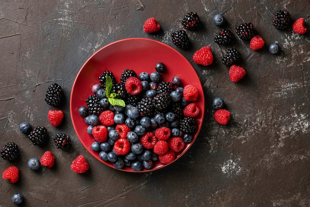 Assorted of berries on red plate. Raspberry, blackberry, and blueberry on black background

