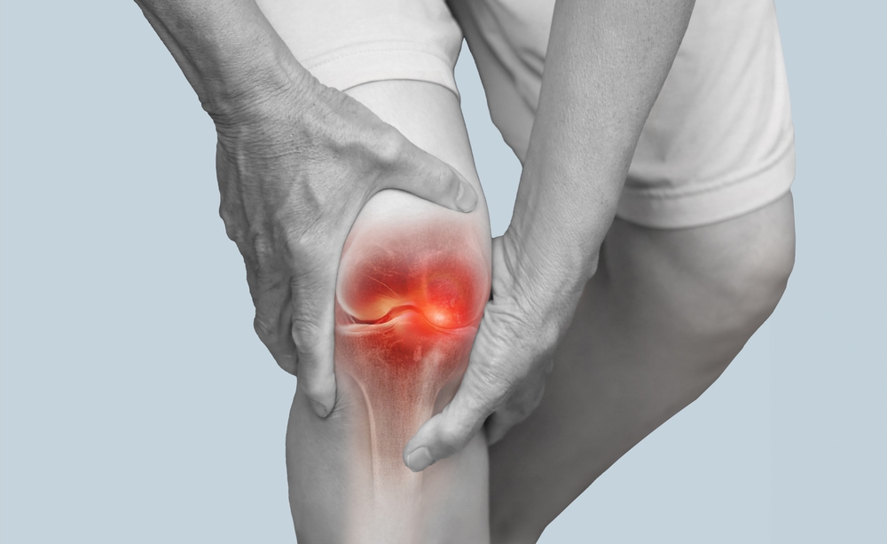Close up of hands holding knee with pain due to degenerative arthritis
