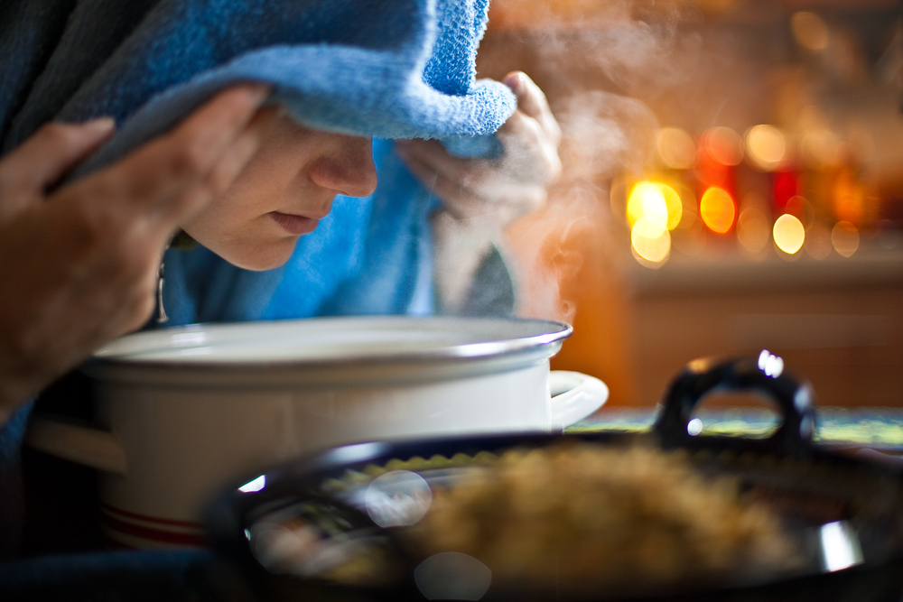 Young woman inhaling chamomile tea steam as an alternative therapy or traditional cure.