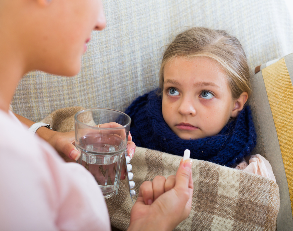 Sick little girl taking medication from worried mother
