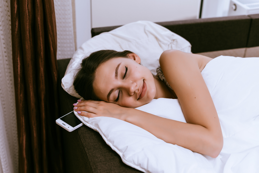 happy young girl is sleeping under a white blanket, she has a day off
