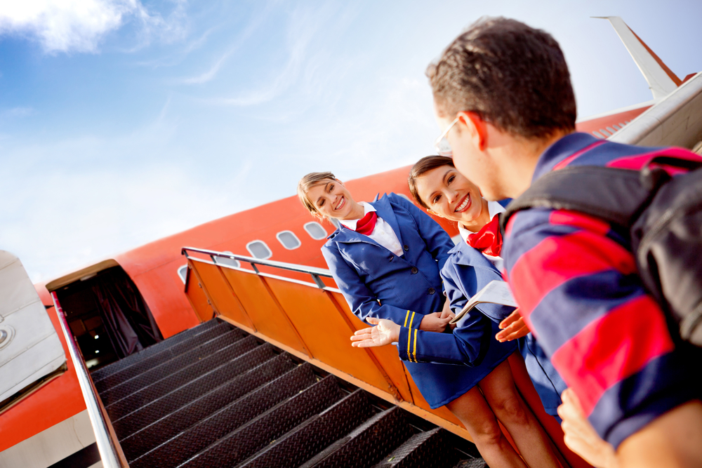 Passenger going into the airplane and air hostesses welcoming him
