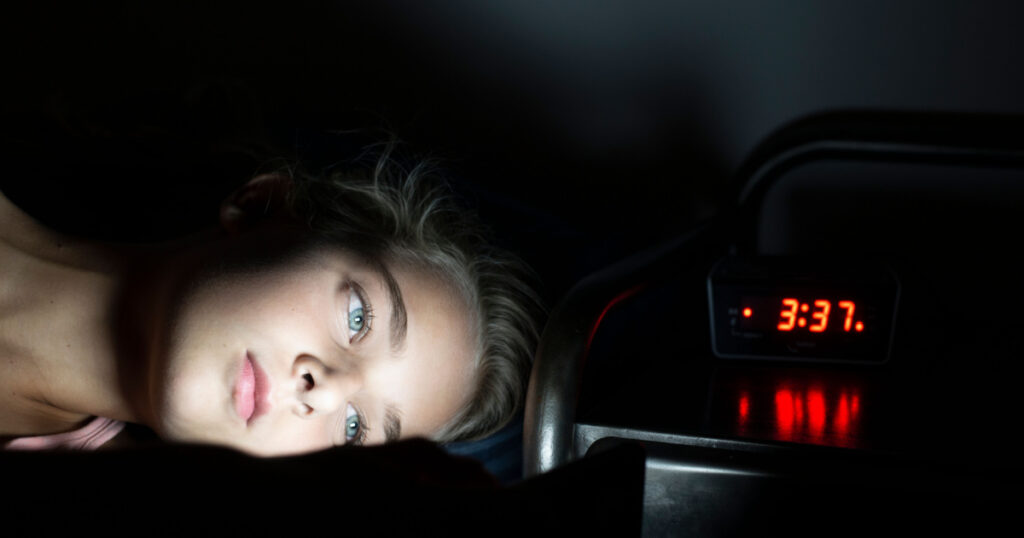 Young girl using smartphone in bed late at night