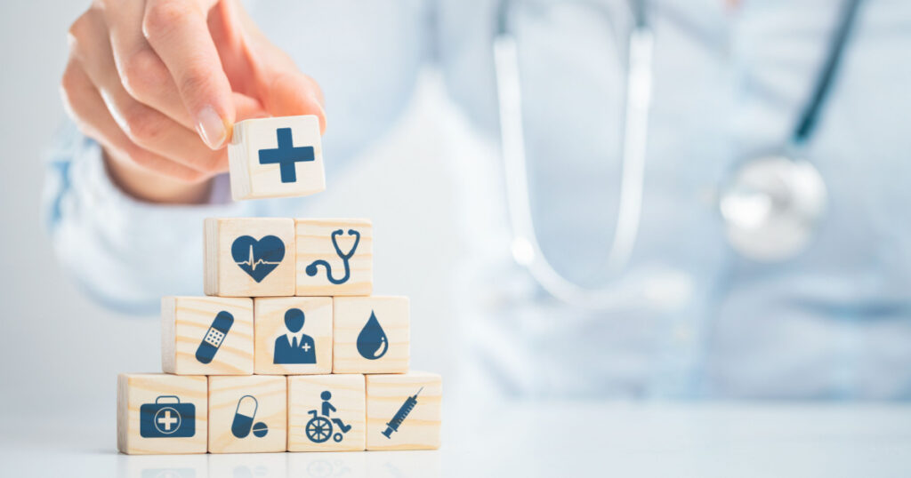 Hand arranging wood block with healthcare medical icon. Health insurance - concept.
