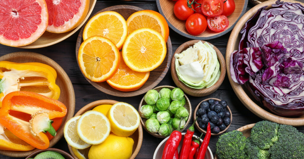 Different products rich in vitamin C on wooden table, flat lay
