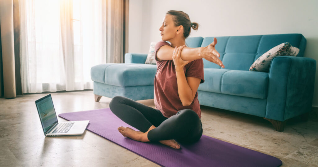 Attractive young woman doing yoga stretching yoga online at home. Self-isolation is beneficial, entertainment and education on the Internet. Healthy lifestyle concept.